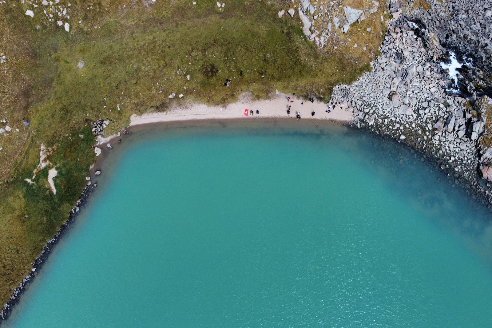 Turquoise water and a small beach on the shore of Ala-Kul, from above