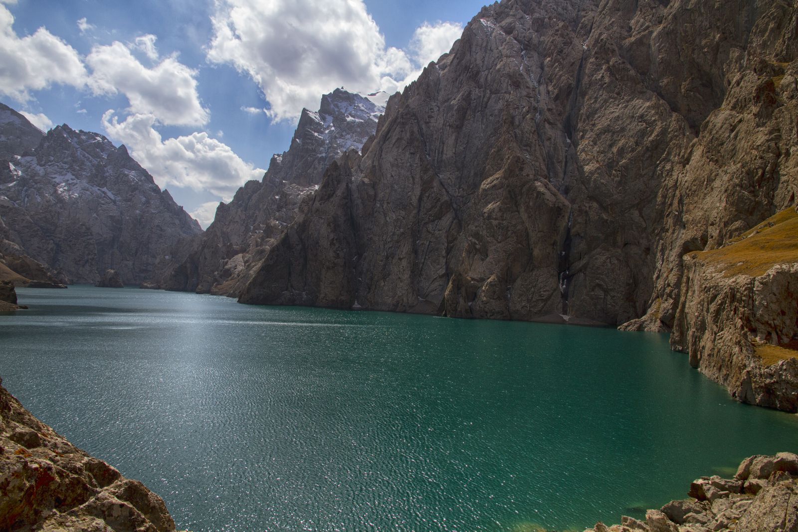 Turquoise Kel-Suu lake between sheer rock walls